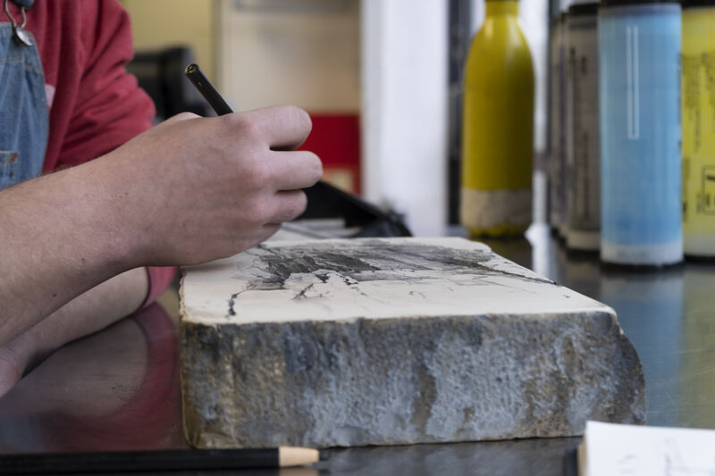 Person drawing onto a slab of stone