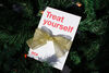 Treat yourself gift voucer with gold ribbon sitting in a Christmas tree