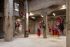 Colourful sculptures hang from a warehouse gallery space 