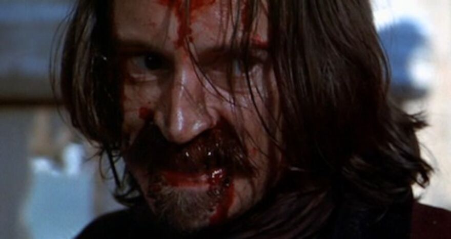 A man with a scary expression on his face and blood all over his face.