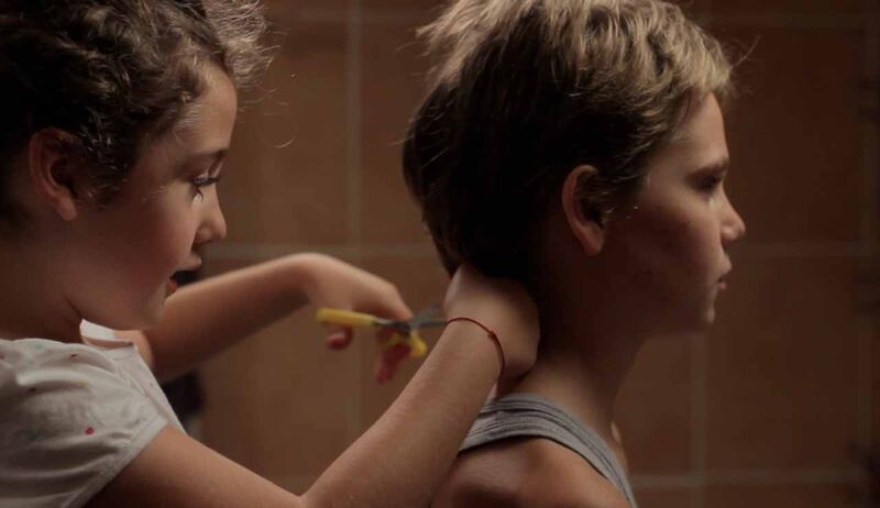 A little girl cuts another child's hair.