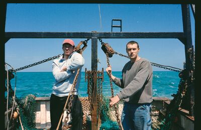 Two young men on a fishing boat in the sun
