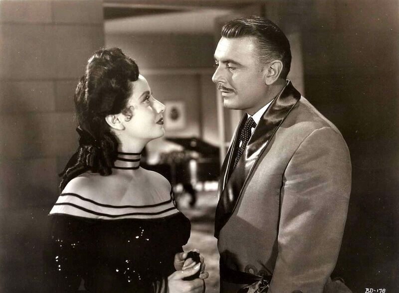 Man and woman in vintage clothing look at one another.
