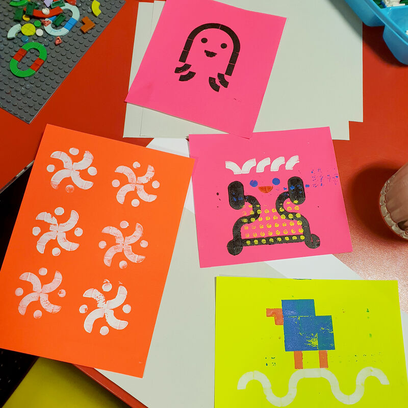 Selection of prints on neon paper, all made by printing with lego dots