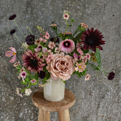 Vase of pink and purple flowers on a wooden stool