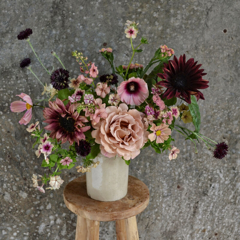 Vase of pink and purple flowers on a wooden stool