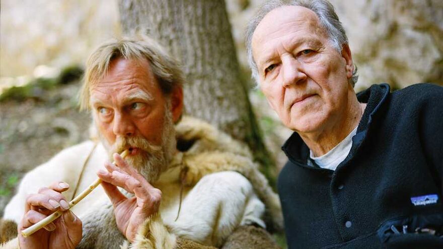 To men, one looks at the camera intensely the other plays on a reed like it's a instrument