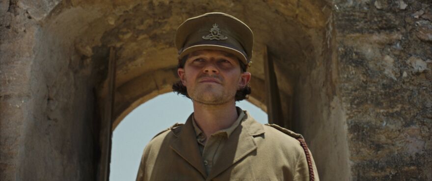 A man in khaki army uniform and an army cap