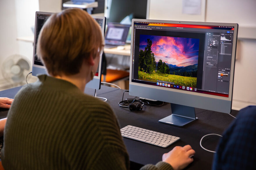 Person using Photoshop on a Mac to edit an image of a landscape