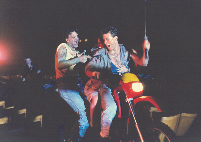 Two people on a motorbike trying to fight off a demon