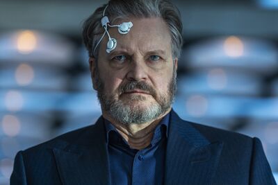 A close view of a man with electrodes stuck to his head, he has a pained expression. Colin firth is the man.