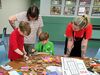 Children and adults making together using recycled cardboard as a DCA staff member looks on