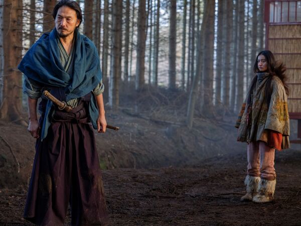 A girl and a man, dressed in Japanese period clothes, stand in a forest.