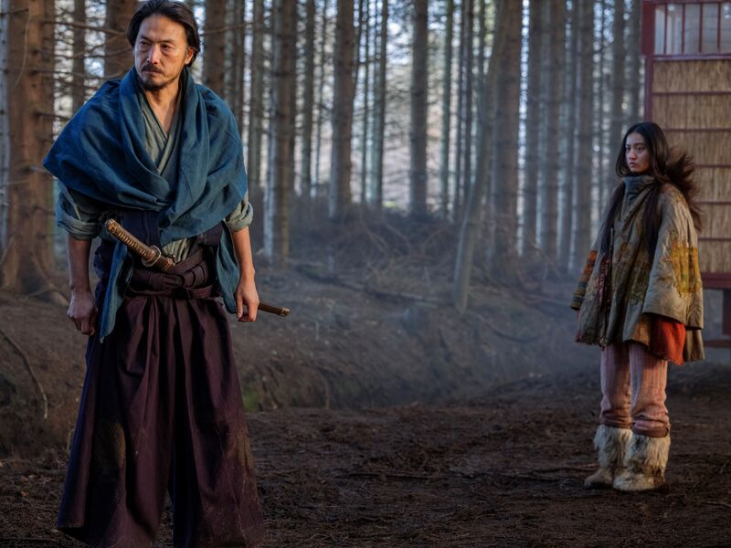 A girl and a man, dressed in Japanese period clothes, stand in a forest.