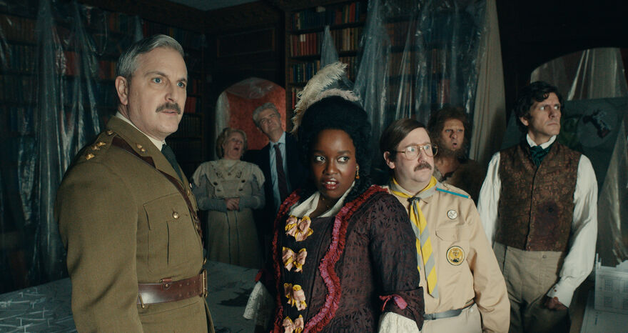 Men and women in clothing from different eras look out at something we can't see