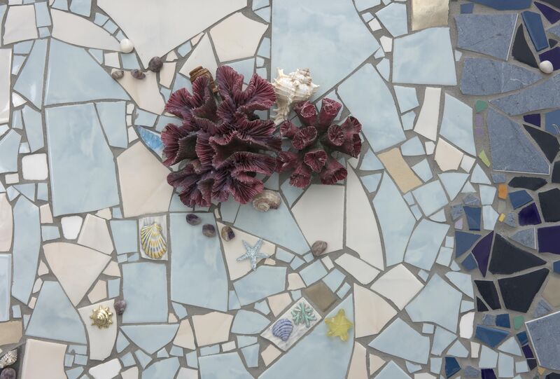 A close-up shot of mosaic pieces from Alex Frost's exhibition. The mosaic pieces are blue and are decorated with shells.