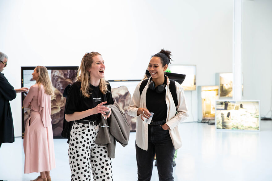 Two people standing in a gallery, smiling and laughing