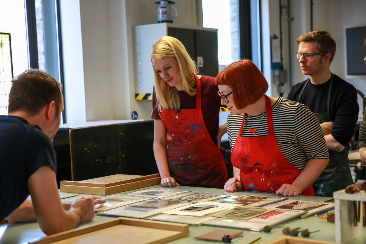 Three people looking at examples of prints created in DCA Print Studio
