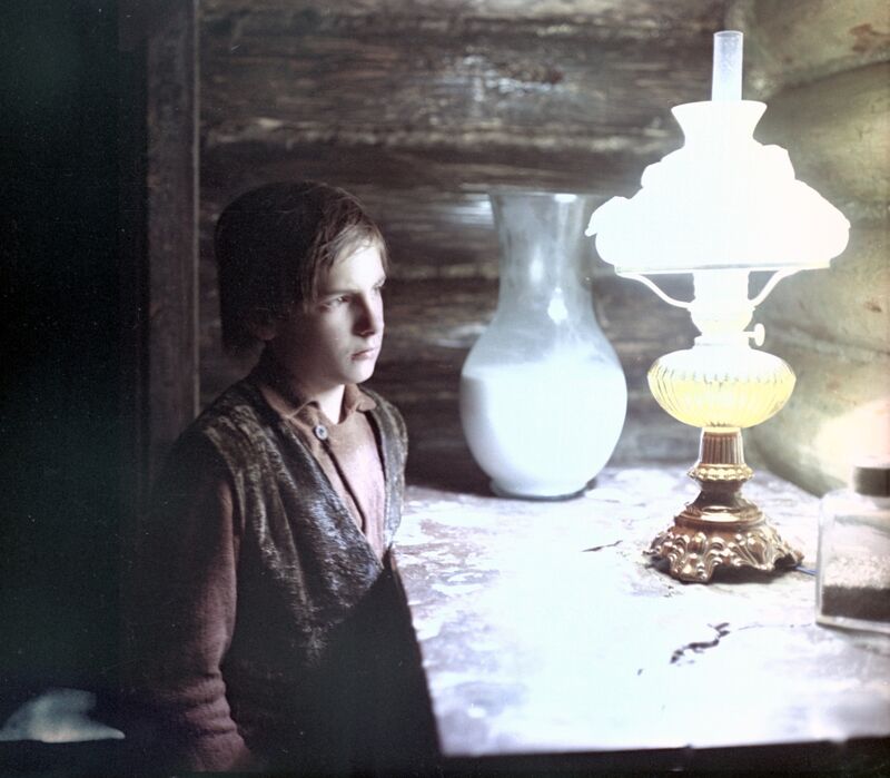 A young man looks at an oil lamp
