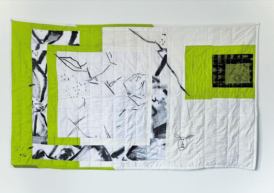 Quilted wall hanging made with green and white fabric with painted elements
