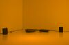 From Timecode exhibition. A room is lit up with orange light. There are speakers and electrical equipment in the room, wired together.