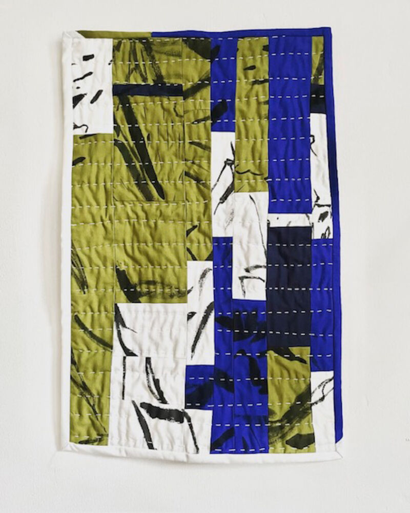 Quilted wall hanging made with green and white fabric with painted elements, blue, white and black fabric with painted fabric