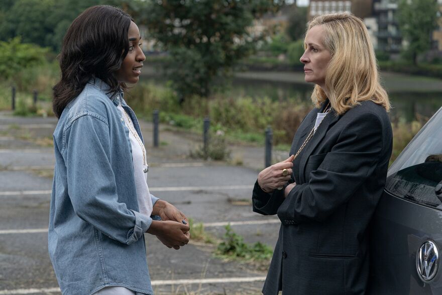 Two woman talk to each other in a tense manner in a carpark.