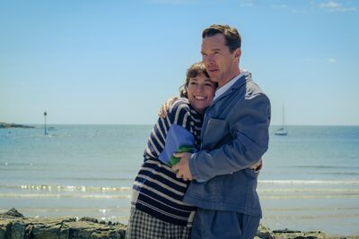A man and woman embrace on a beach.