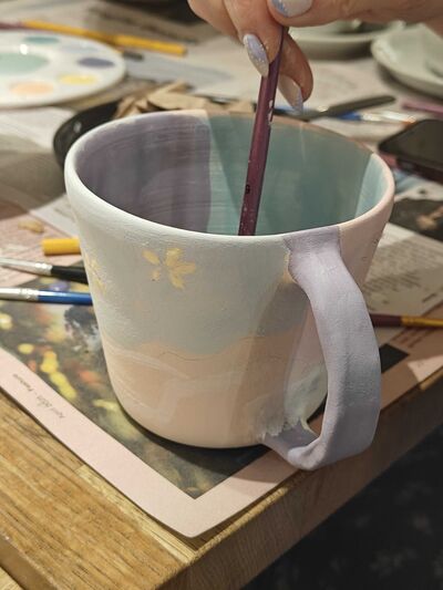 close up of person painting the inside of a mug