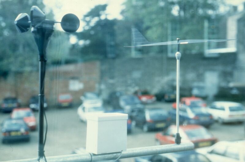 A satellite dish with two dials on it overlooks a car park.