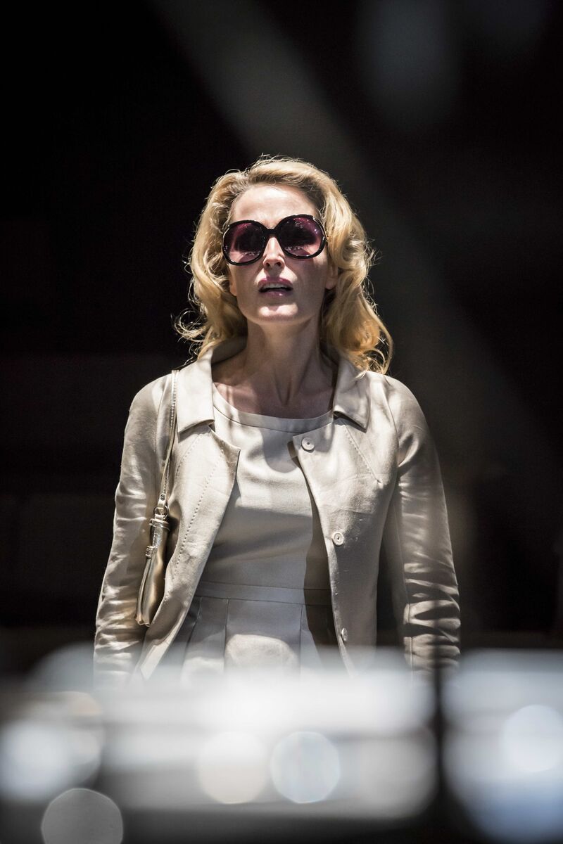 A blonde woman wearing sunglasses stands on stage.