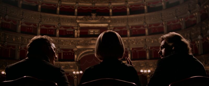 Three people sitting on a stage in a theatre
