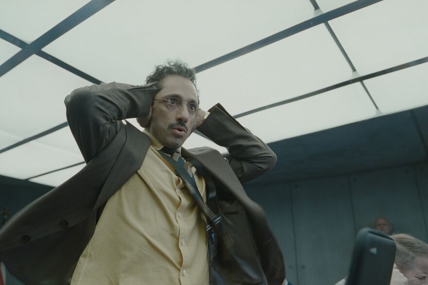 A man in a suit holds his head in his hands