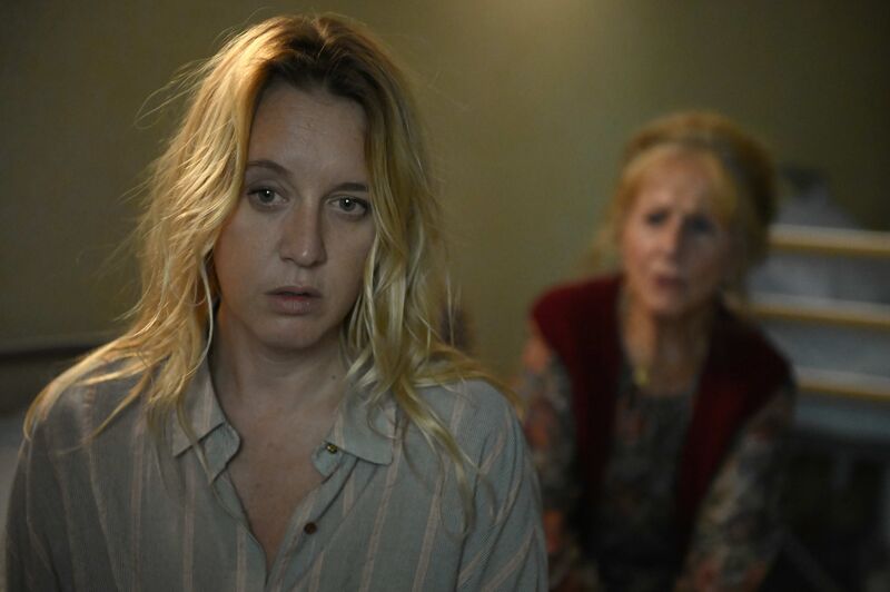 A blonde woman in pyjamas looks shocked, while an older woman talks to her.