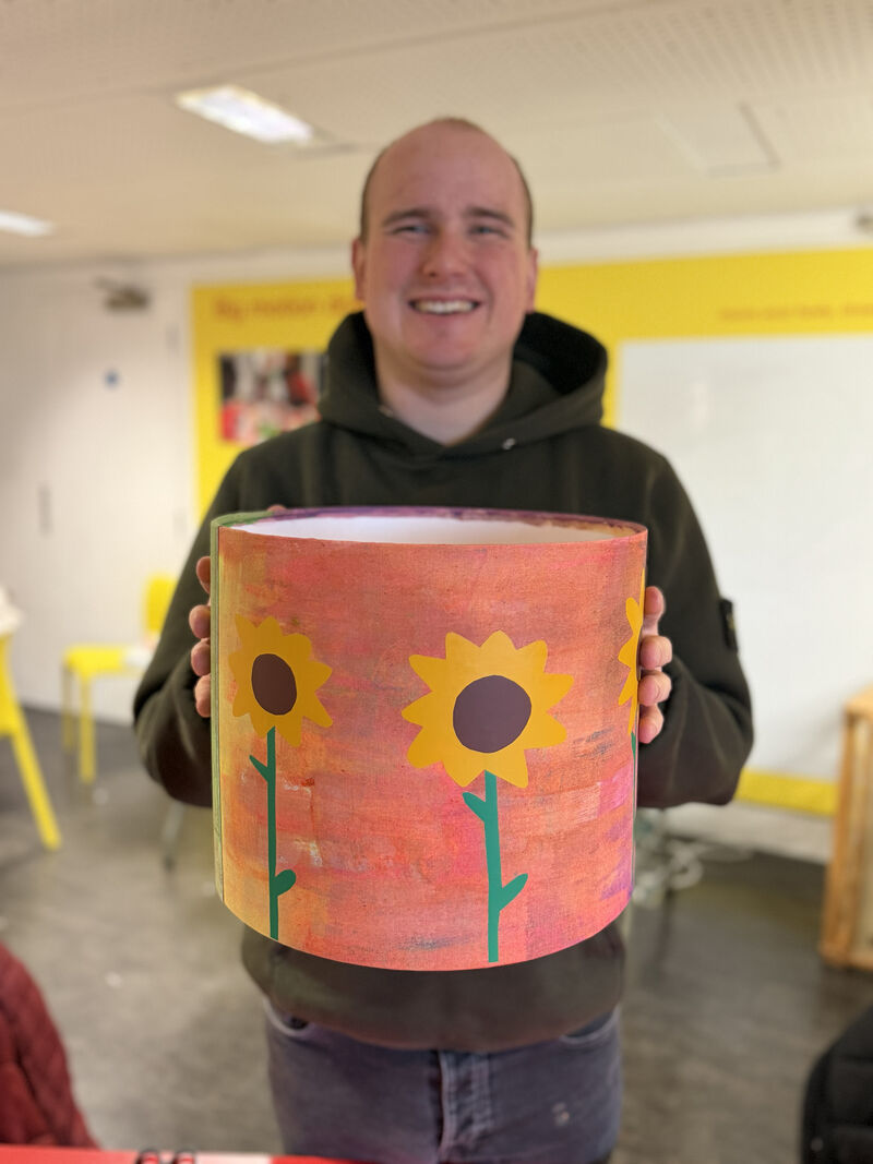 Person holding a lampshade decorated with sunflowers