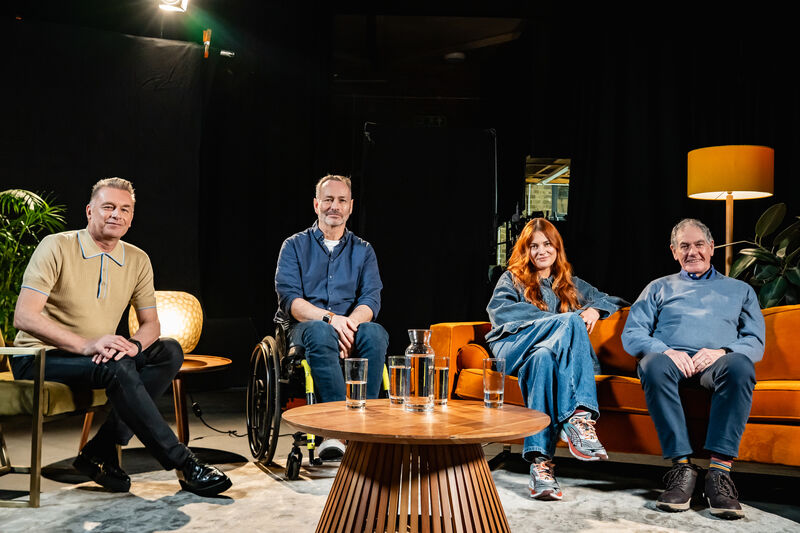 A group of people sit looking at the camera in a talk show