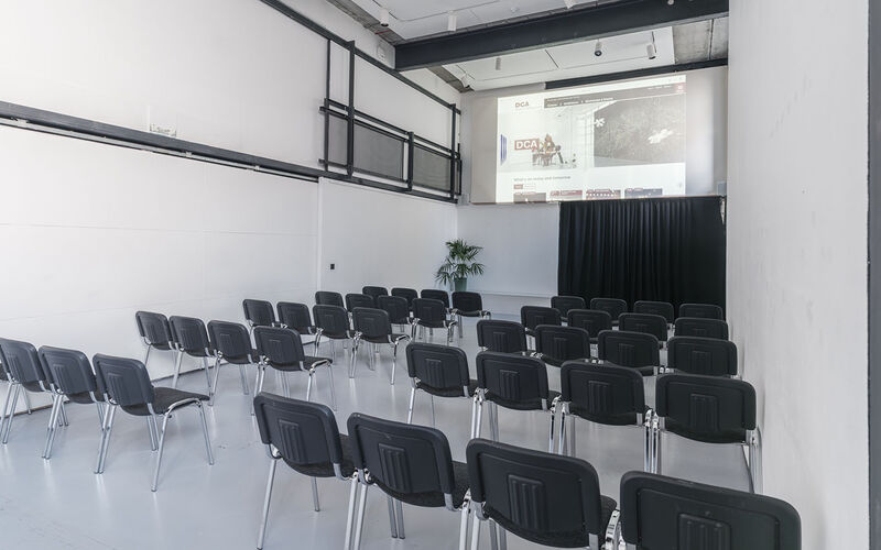 a large room with a screen in the front and chairs in theatre style