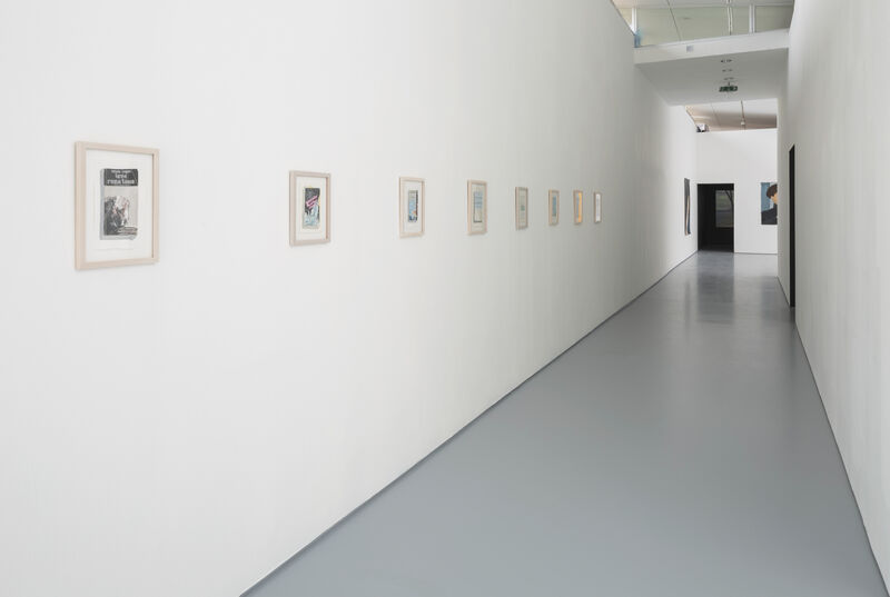 Photograph of framed drawn book covers, in a line on a white wall, going off into the distance. 