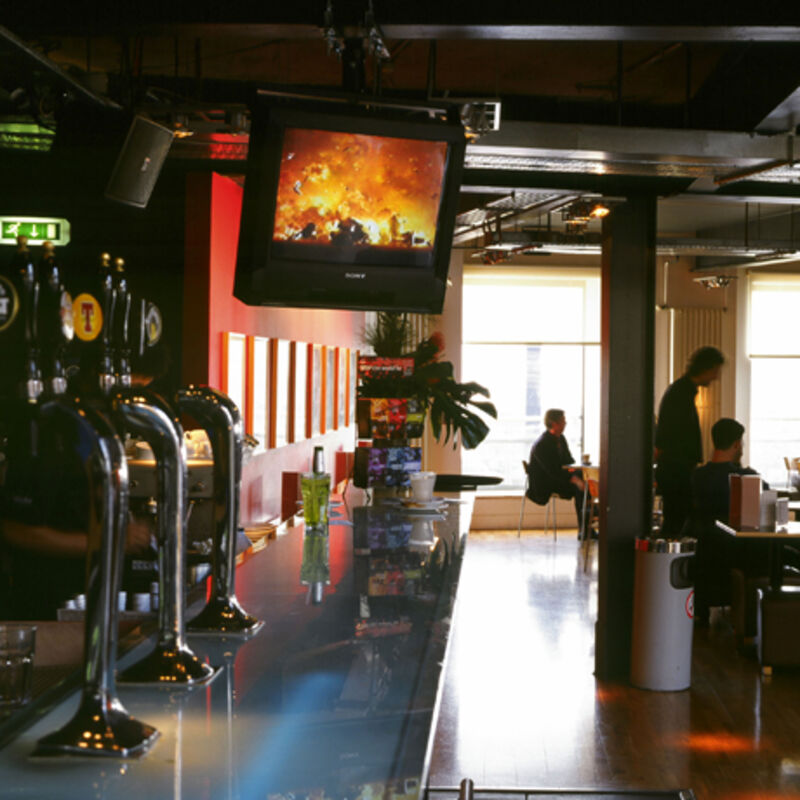 Jute Cafe Bar during Plunder at DCA Galleries. A televisions screen shows a fiery sky and an explosion.