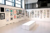 Createspace with walls covered in framed prints and white benches in the middle of the room