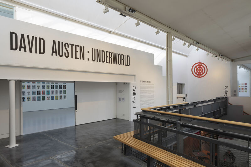 Image shows the outside of DCA gallery, taken from the concourse looking towards the entrance. Text above the doorway reads David Austen: Underworld in black block capitals. 