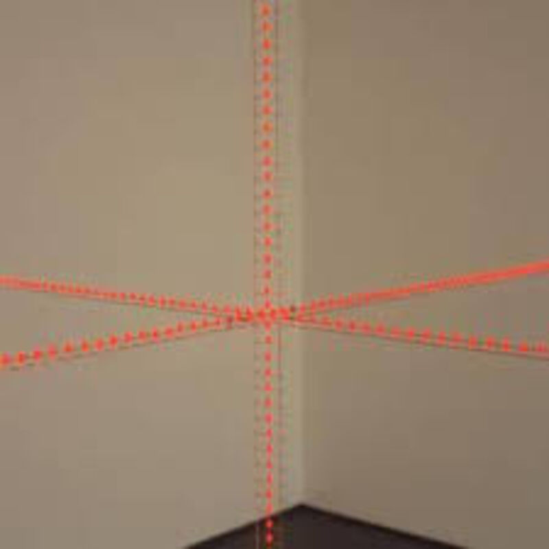 Work by Grönlund\Nisunen - orange thread is arranged in a cross shape in front of a wall.