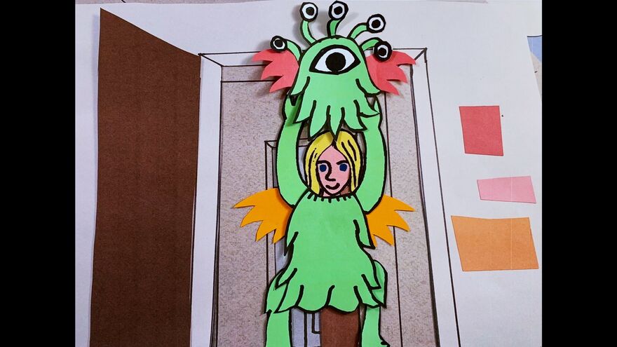 A cardboard cut out of a blonde girl lifting the head off an alien costumer