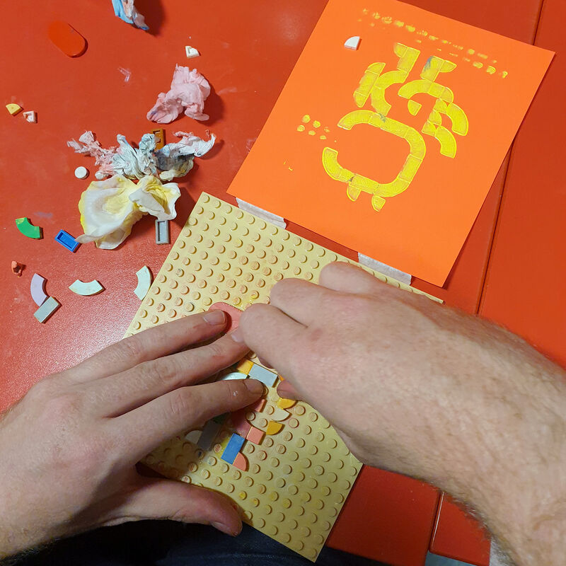 Person creating a design for printing using lego dots