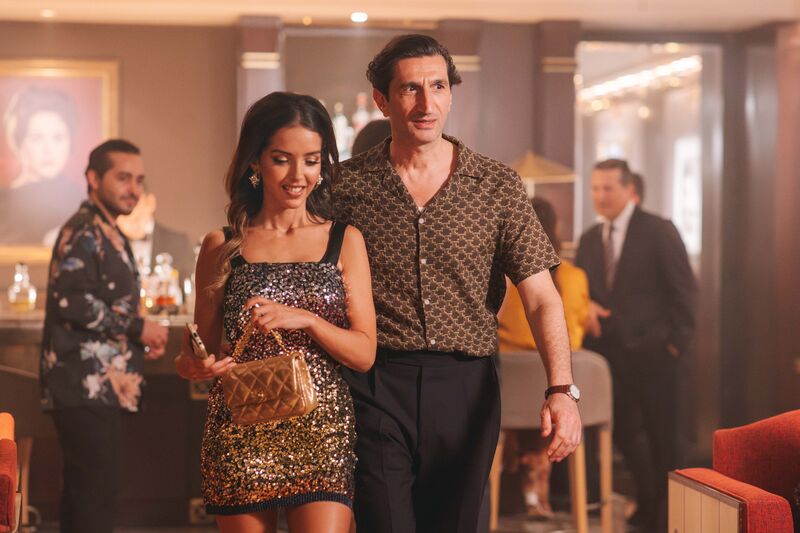 A man in patterned shirt and glamorous women in a sparkly dress leave a casino