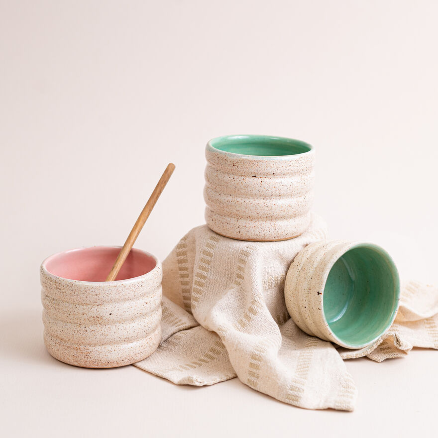 Three ceramic mugs without handles and with different coloured glaze on the inside