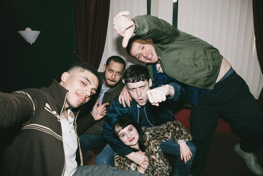 Four young men and a young woman pose for the camera
