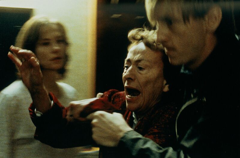 A woman screams and lifts up her arm while a man holds her back