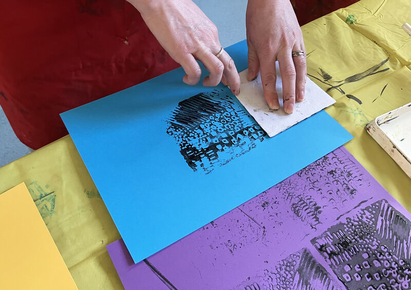 Person printing a pattern onto a blue piece of paper
