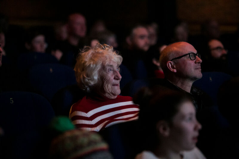 A woman sits in DCA Cinema watching a film.